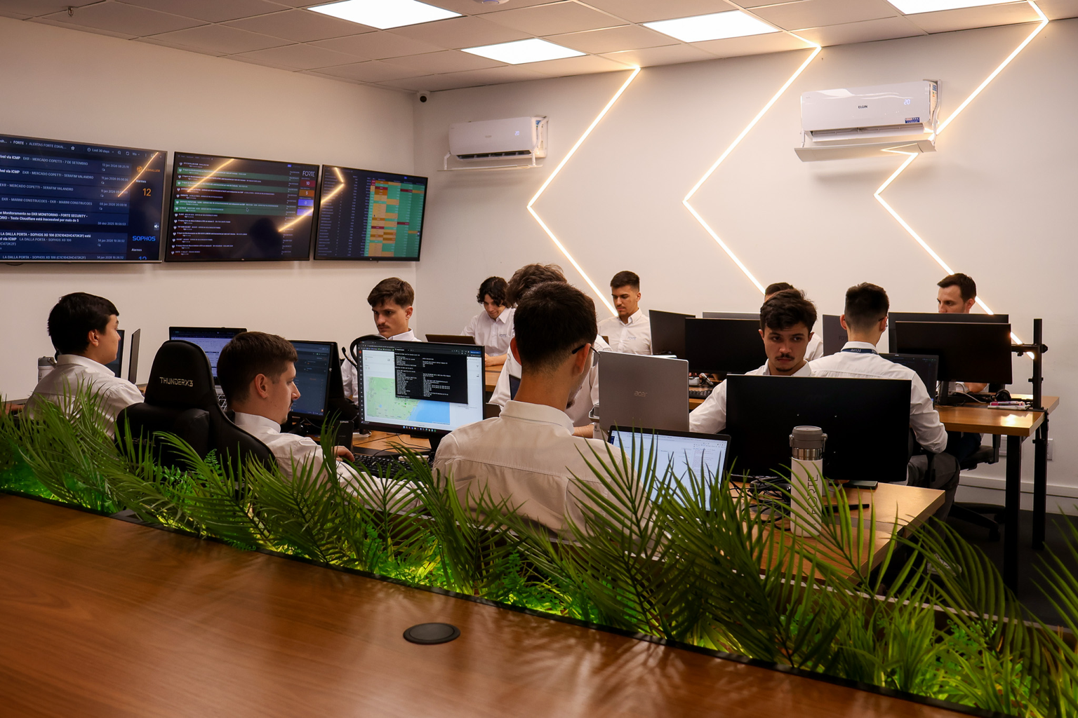 Equipe da Forte no NOC trabalhando em computadores com dashboards de monitoramento em telas